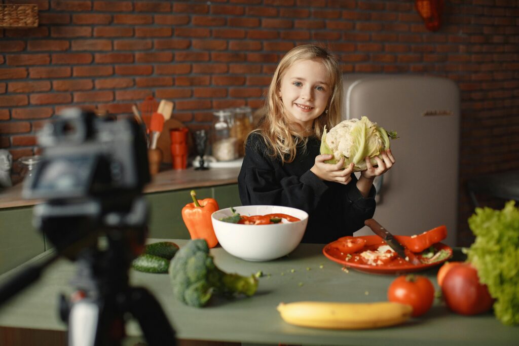 A young girl holds a cauliflower while making a fresh "Kids’ nutrition tips in vegetable recipes for kids" salad in a kitchen.